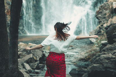 Rear view of woman standing against waterfall