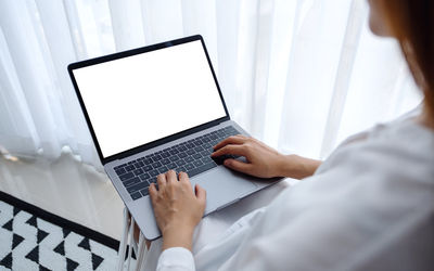 Midsection of woman using laptop at home