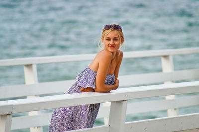 Portrait of smiling young woman by railing