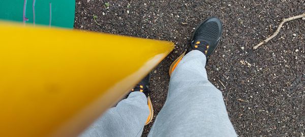 Low section of person standing on yellow road