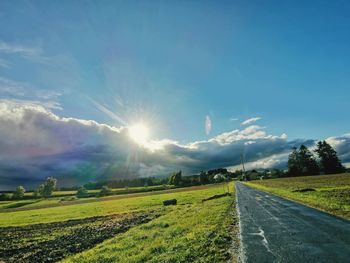 Scenic view of road amidst field against sky