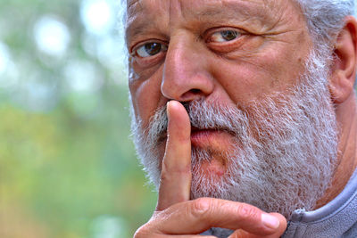 Close-up portrait of man with finger on lips