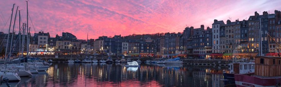 Illuminated cityscape against sky at sunset
