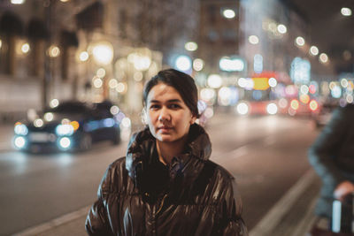 Portrait of man standing on city street at night