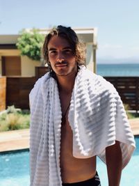 Portrait of shirtless man standing at poolside