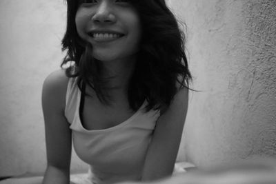 Young woman smiling while standing against wall at home