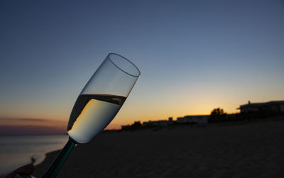 Close-up of beer glass against sunset sky