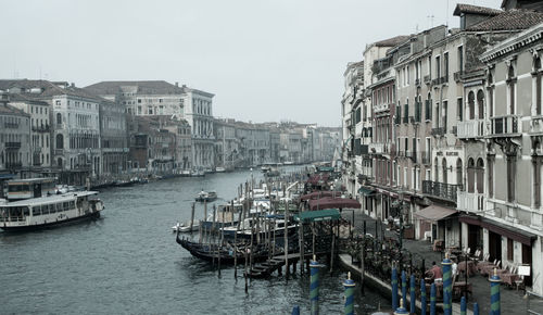 Boats moored at canal against buildings in city