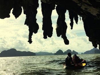 Rear view of people boating on sea seen through cave