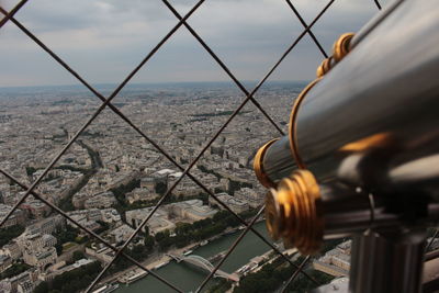 Perspective of paris from the eiffel tower, telescope view along patterned fence 