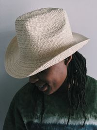 Close-up of woman wearing hat against wall