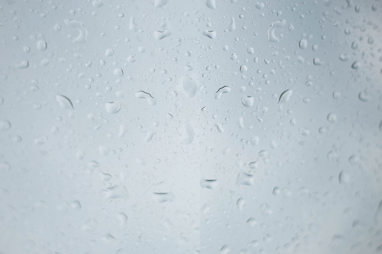 CLOSE-UP OF WET GLASS WINDOW IN RAINY SEASON