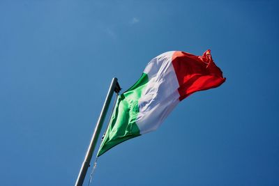 Low angle view of flag against clear blue sky