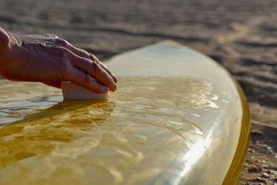 Close-up of hand waxing a surfboard