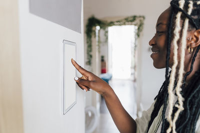 Smiling woman using home automation on wall at home