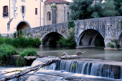 Arch bridge over river against buildings