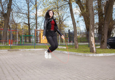 Full length portrait of woman on footpath in park