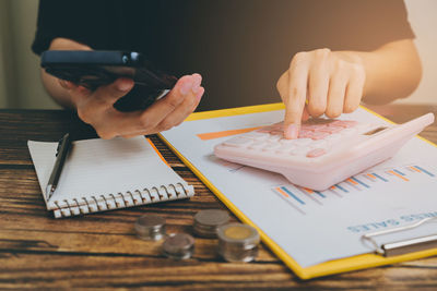 Cropped hands of man using mobile phone on table