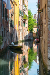 Boat on canal amidst buildings in city