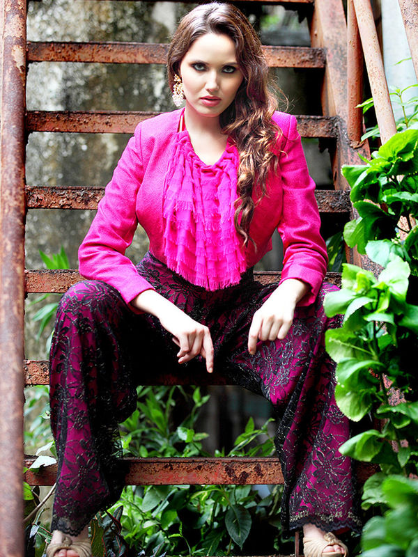 PORTRAIT OF SMILING YOUNG WOMAN SITTING ON PURPLE OUTDOORS