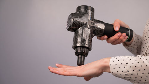 Cropped hand of man repairing equipment against gray background