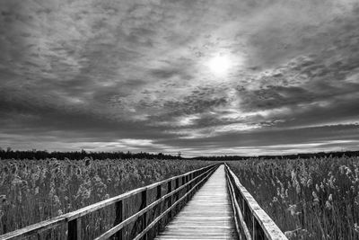 View of footpath on field against cloudy sky