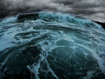 Wave rushing towards shore against sky