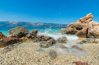 Rocks in sea against blue sky