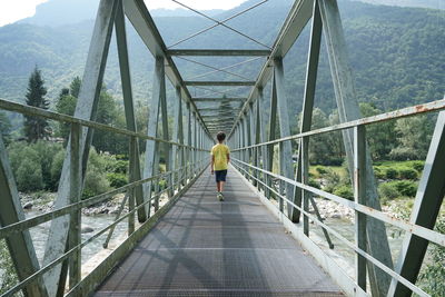 Rear view of boy walking on footbridge