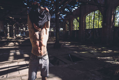 Man removing t-shirt while standing on footpath