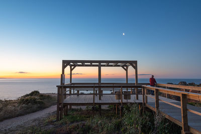 Pier over sea against clear sky during sunset