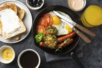 Breakfast food in pan, sausages, fried eggs, tomatoes. morning coffee