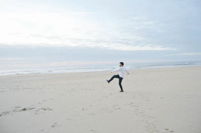 Full length of man standing on beach against sky