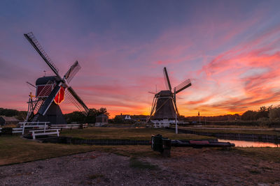 Traditional windmill against cloudy sky during sunset