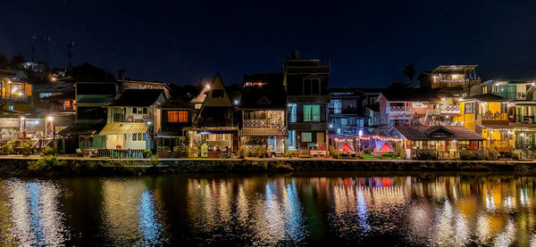 Illuminated buildings by river against sky at night, home village beautiful in night, townhouse