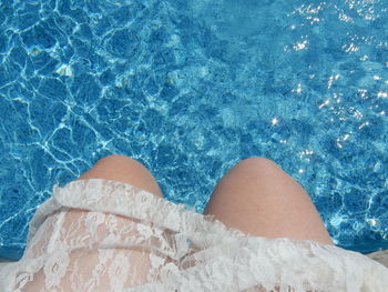 Midsection of woman sitting at poolside