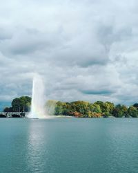 Scenic view of waterfall against cloudy sky