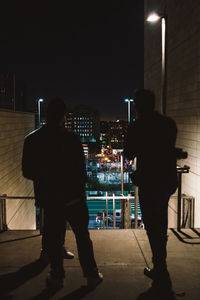 Rear view of man standing in illuminated building at night