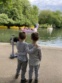 Rear view of children on shore against trees