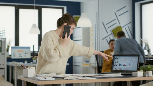 Side view of woman using mobile phone in office