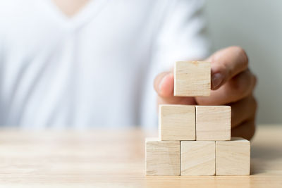 Midsection of man stacking wooden toy blocks at table