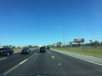 Cars on highway against clear blue sky