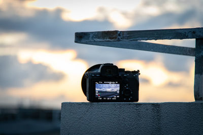 Close-up of camera photographing against sky