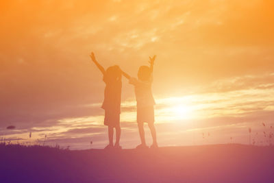 Silhouette people standing against sky during sunset