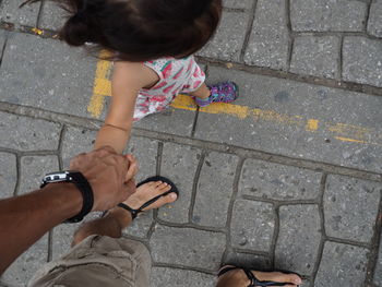 High angle view of girl  holding hands with man on cobblestone streets