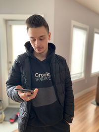 Young man looking away while standing at home