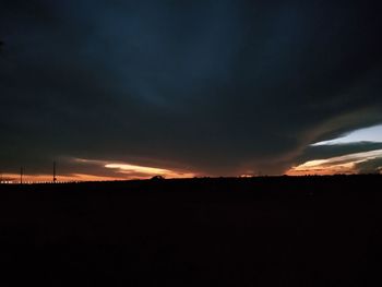 Silhouette landscape against dramatic sky during sunset