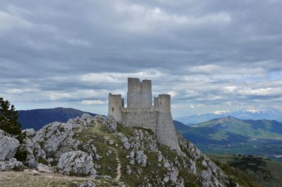 Castle on mountain against cloudy sky