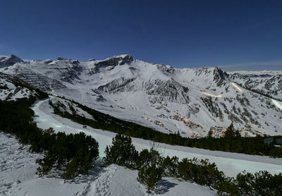 Scenic view of snowcapped mountains against clear blue night sky