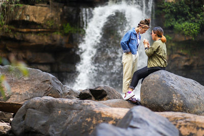 Rear view of people sitting on rock